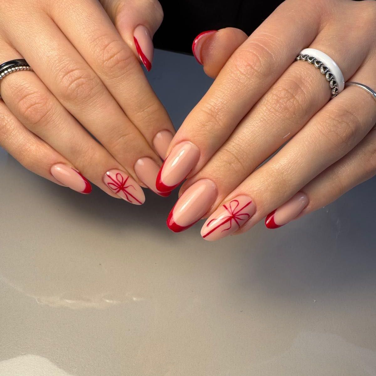 Manicure z czerwonym wzorem French i motywem kokardki